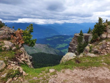 Rotsblokken op een uitzichtpunt met het dal ver beneden – Rasciesa di Fuori en het topkruis, Val Gardena